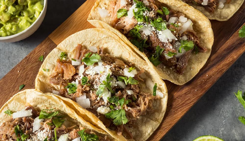 Plate of shredded pork tacos topped with cilantro and onions served with guacamole in Tahoe Vista, CA.