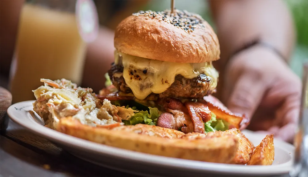 Close-up of a gourmet burger with bacon and melted cheese served with fries at a local eatery in Tahoe Vista, CA.