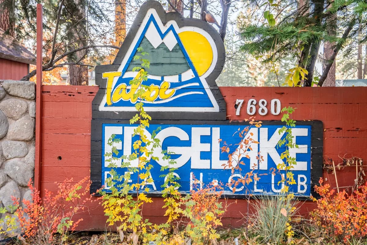 Lakeside patio with loungers and umbrella table on grass beside the sandy beach