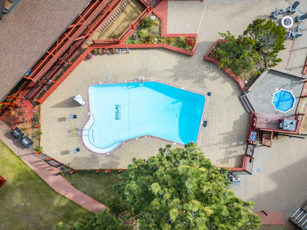 Aerial of red lakeside lodges with courtyard, hot tub, and pool by the beach