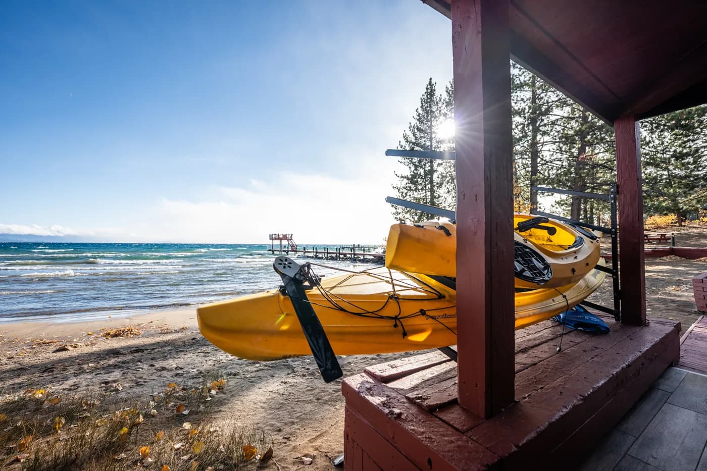 Yellow kayaks on a lakeside deck with a scenic view of the water and trees.