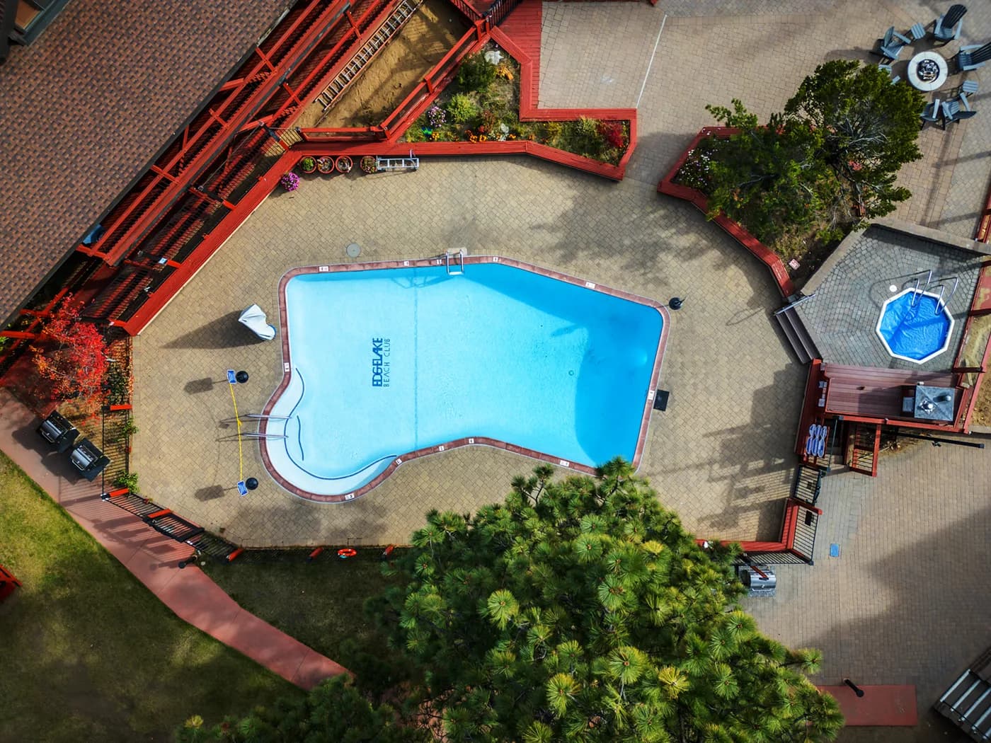 Aerial view of an outdoor pool with lounge chairs surrounded by a deck and seating area.